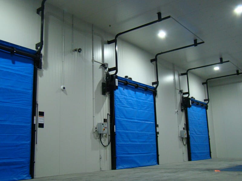 Three blue FasTrax FR Doors installed in a cold storage facility.