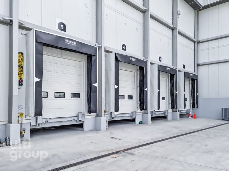 Row of industrial loading docks with black dock seals and white sectional doors.
