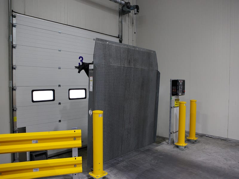 Vertical Storing Dock Leveller in upright position inside a warehouse facility.