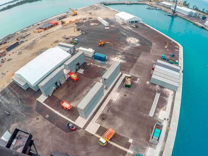 Aerial view of a port construction site with temporary buildings and containers.