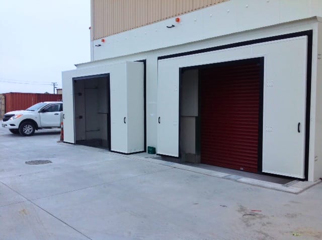 Two white insulated sliding doors installed on an external warehouse wall.