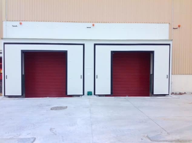 Two red industrial roller doors installed in white dock loading bays.